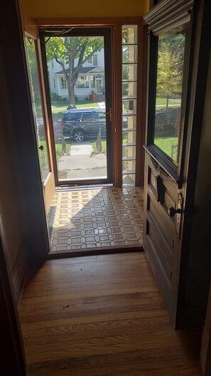 A wooden hallway with a door leading to a driveway.