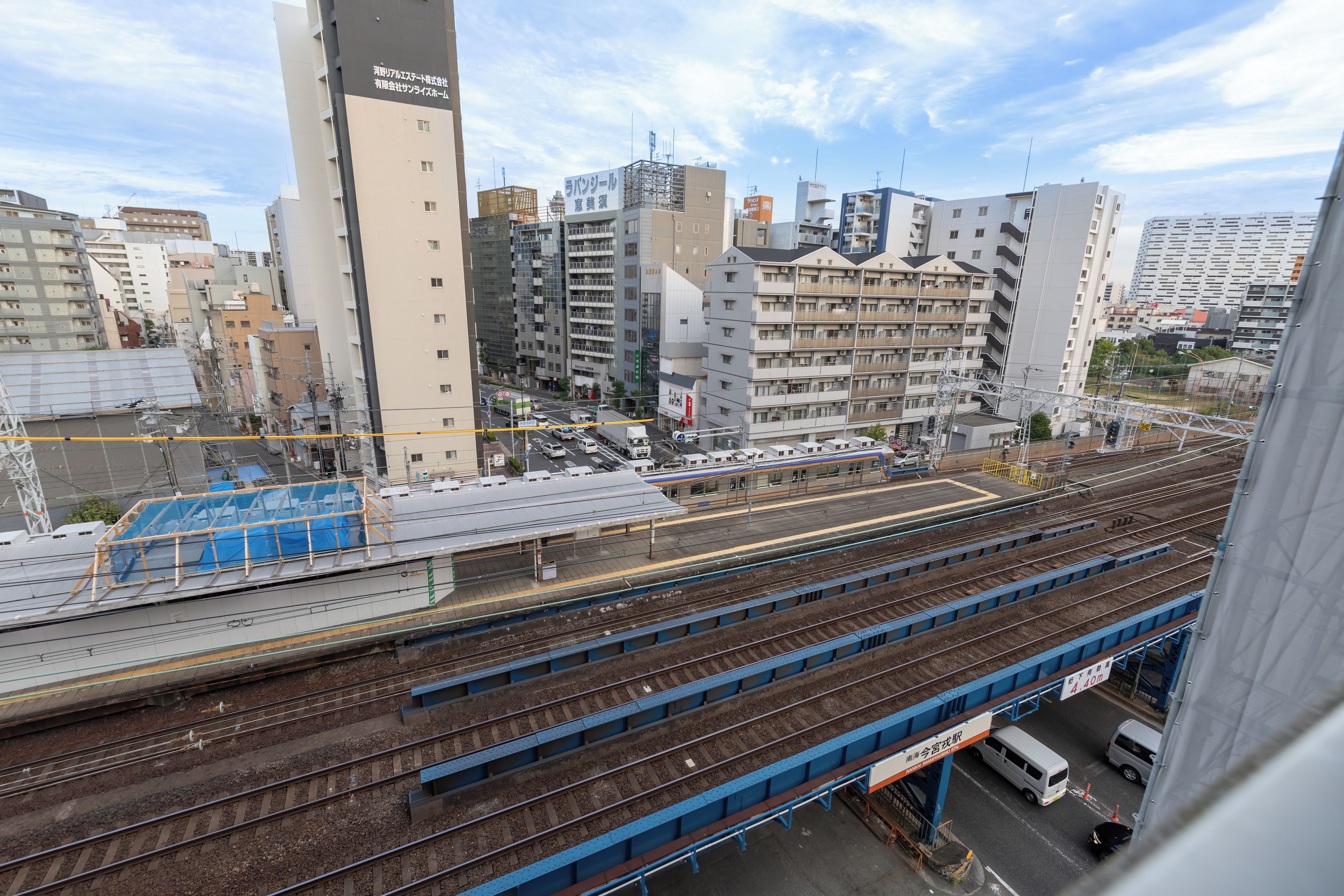 Ein mehrgeschossiges Bahnhofsgebäude mit Gleisen und Bahnsteigen, umgeben von verschiedenen Gebäuden.