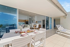 Ein Balkon mit Esstisch für Zwei, einer Couch und einer Lounge-Ecke mit Liegestühlen.