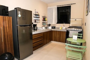 Eine kompakte Küche mit Kühlschrank, Herd und einer kleinen Essecke mit Tisch und Stühlen.
