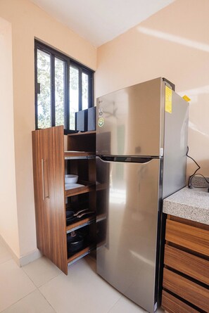 Eine Küche mit einem Edelstahl-Kühlschrank, Holzschränken und einem Fenster.