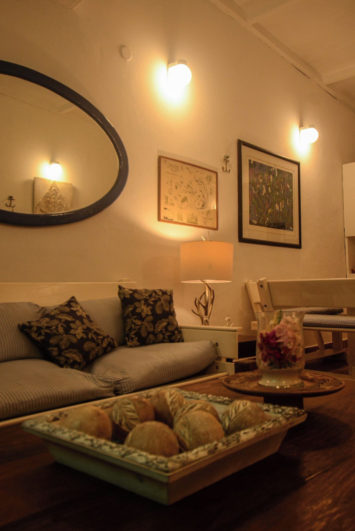 Una sala de estar acogedora con un sofá, una mesa de centro con una bandeja de pan, una lámpara e iluminación en la pared.