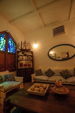 Una sala de estar acogedora con una mesa de centro de madera, un sofá, una mesita auxiliar y un modelo decorativo de barco.