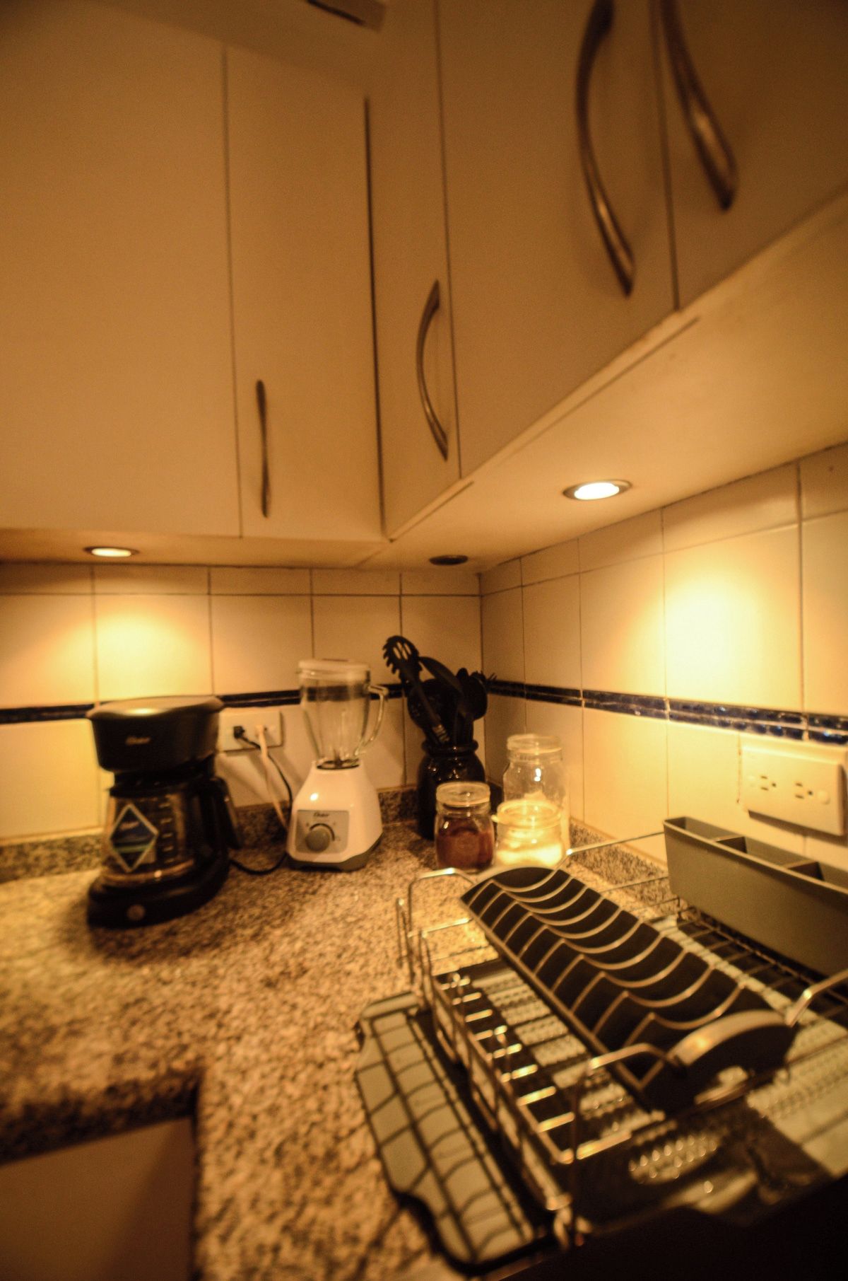 Una cocina con cafetera, licuadora y escurreplatos.