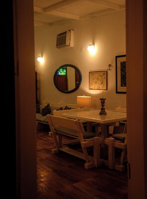 Un área de comedor con un espejo redondo, lámparas fijadas a la pared y una mesa con sillas.