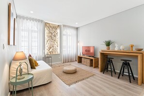 Un soggiorno moderno con un divano, una TV, un tavolo in legno con sgabelli e un elemento decorativo a parete.