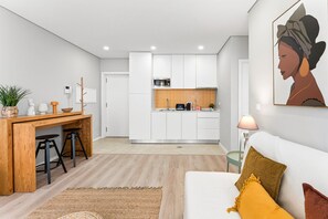 A modern kitchen with white cabinets, a wooden countertop, and a dining area with stools. - GuestReady-Modern Retreat in Vila Nova de Gaia (Vila Nova de Gaia)