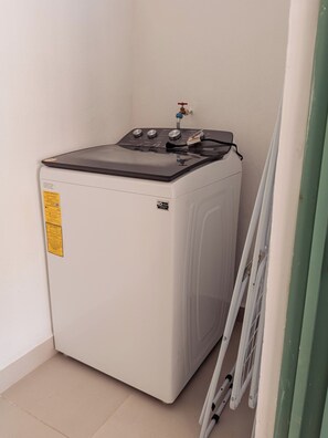 A compact, white washing machine in a corner with a small water inlet. - Casa Rita: Colonial Gem + Pool | Paseo Montejo (Merida)