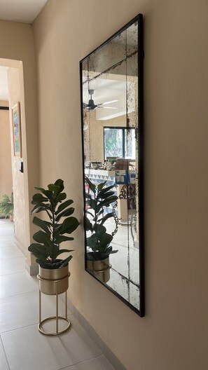 A hallway with a large mirror, a potted plant, and a ceiling fan. - Casa Rita: Colonial Gem + Pool | Paseo Montejo (Merida)