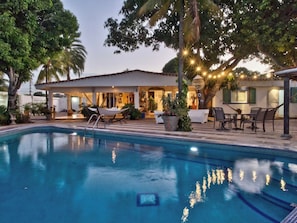 Ein Schwimmbecken mit Liegestühlen und einer überdachten Terrasse.