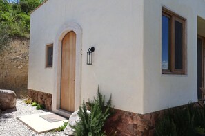 Ein Gebäude mit einer Holztür, einem kleinen Fenster und einem steinernen Fundament.