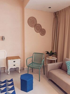 A living room with a sofa, a chair, a small table with a plant, and a decorative wall piece. - Casa  Alberca + Garaje | 2 cuadras Paseo Montejo (Merida)