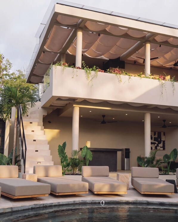 Un edificio moderno con piscina, zona de estar exterior y una escalera.