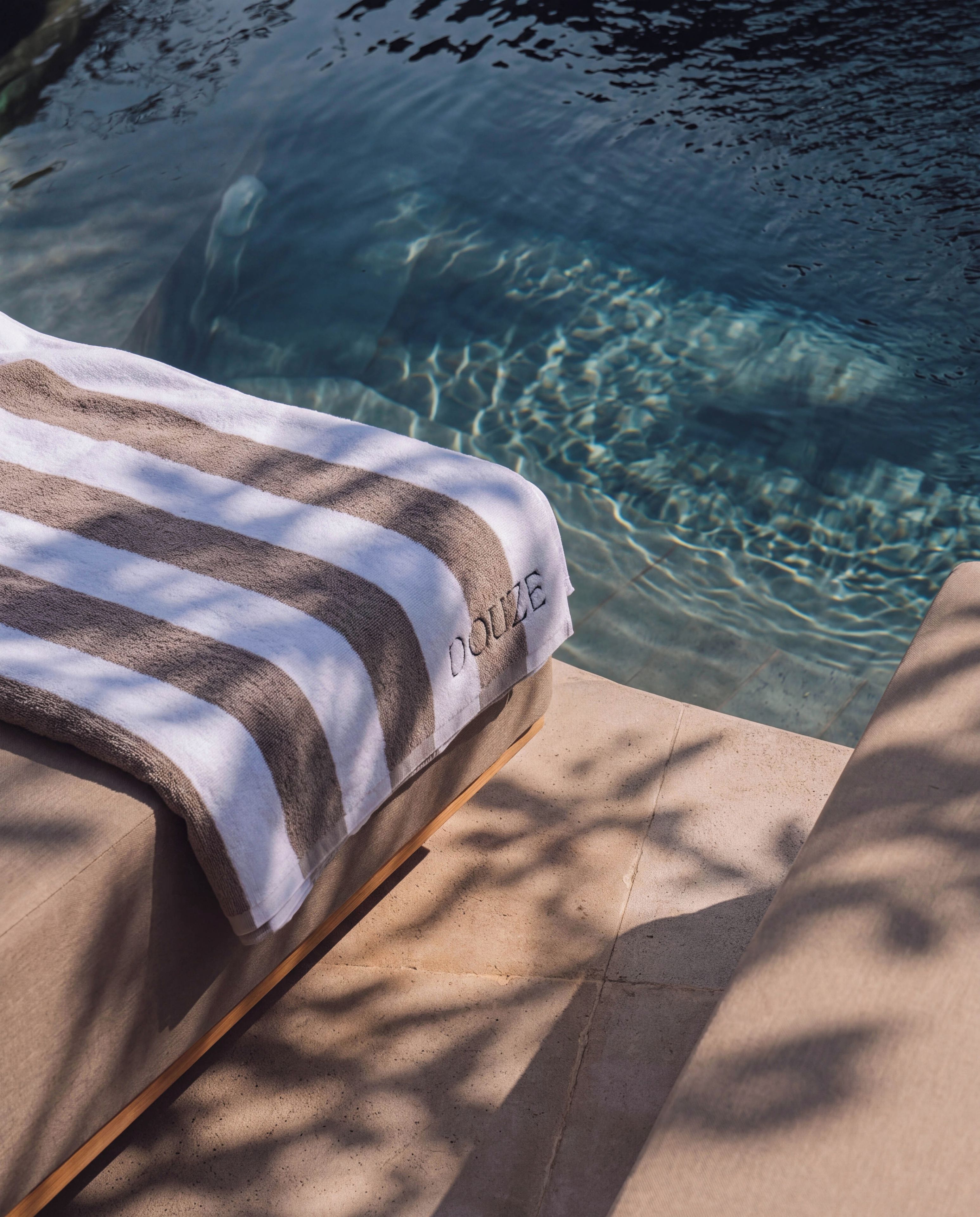 Zona junto a la piscina con una toalla y una pileta.