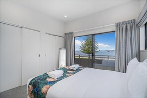 A hotel room with a bed, a window with a view of the sea, and a balcony. - Soleil by the Sea (Whitianga)