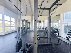 A gym with exercise equipment, large windows, and a concrete ceiling. - The Green & Blue Hideaway: Luxury 2BR Apartment (Punta Cana)