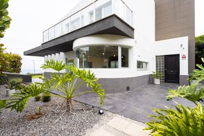 Um edifício moderno com fachada de vidro curva, telhado plano e porta preta.