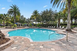 A swimming pool with a curved edge, surrounded by lounge chairs and palm trees. - Modern 3BR Orlando Escape | Pool & Theme Parks (Orlando)