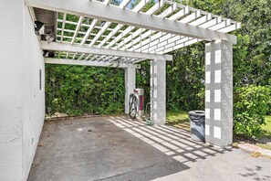 A covered outdoor area with a concrete floor, a bicycle, and a trash can. - Modern 3BR Orlando Escape | Pool & Theme Parks (Orlando)