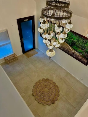 A staircase with a decorative chandelier, a wall-mounted aquarium, and a patterned rug. - The Douglas House | 3BR Spring Hill Escape (Spring Hill)