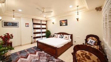 A bedroom with a large bed, a ceiling fan, a window with curtains, and a wall-mounted light fixture.