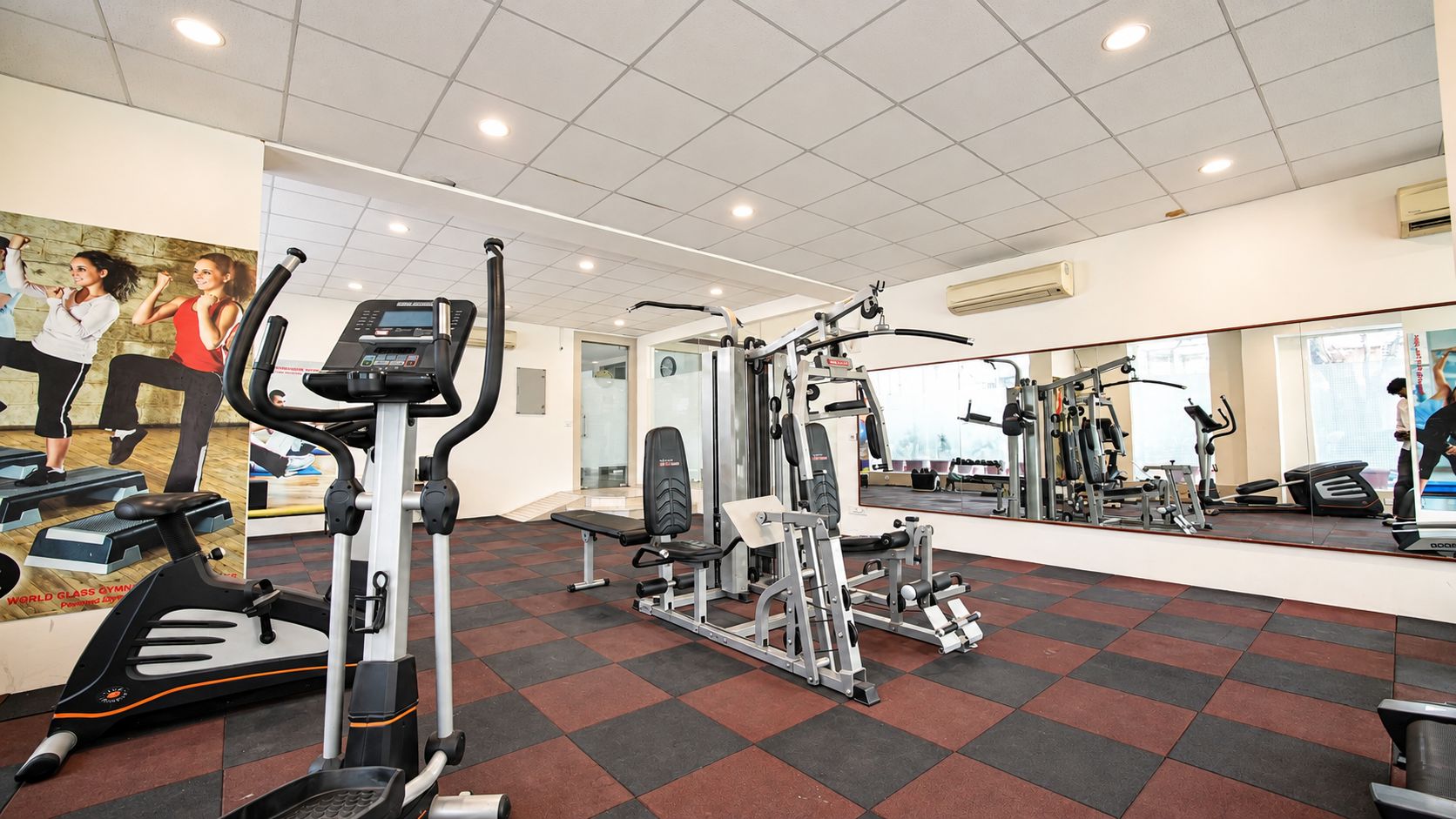 Une salle de sport équipée de machines de cardio, d’appareils de musculation et dotée d’un mur avec des miroirs.