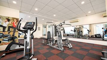 Une salle de sport équipée de machines de cardio, d’appareils de musculation et dotée d’un mur avec des miroirs.