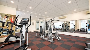 Une salle de sport équipée de machines de cardio, d’appareils de musculation et dotée d’un mur avec des miroirs.