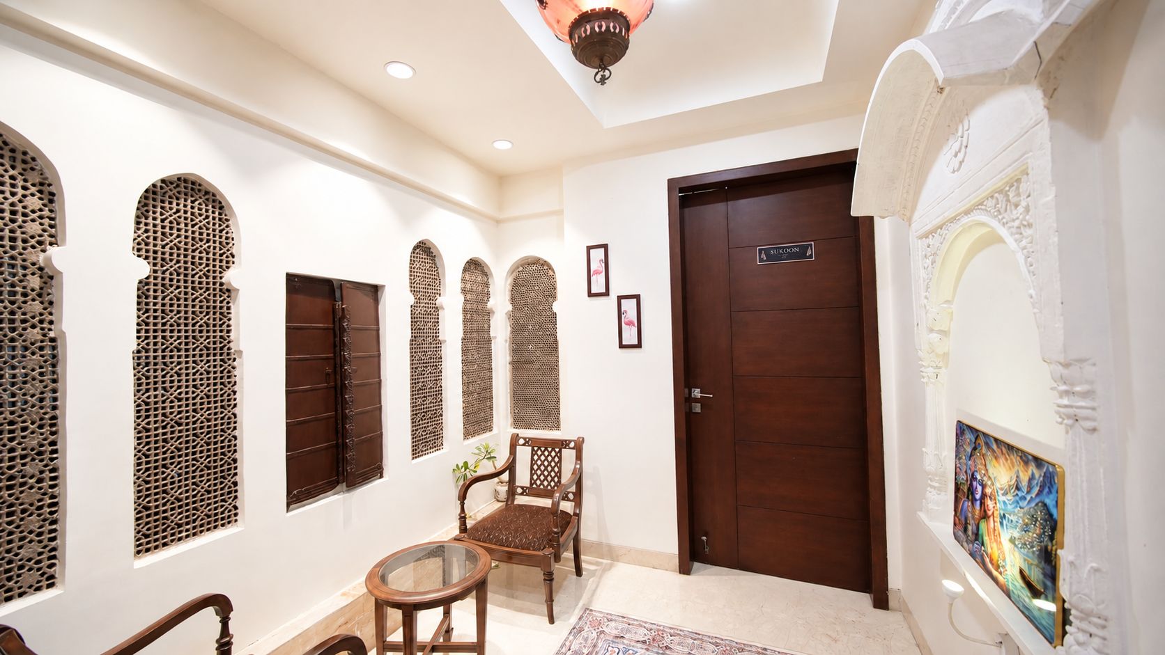 A hotel lobby with a wooden door, a chair, and decorative screens.