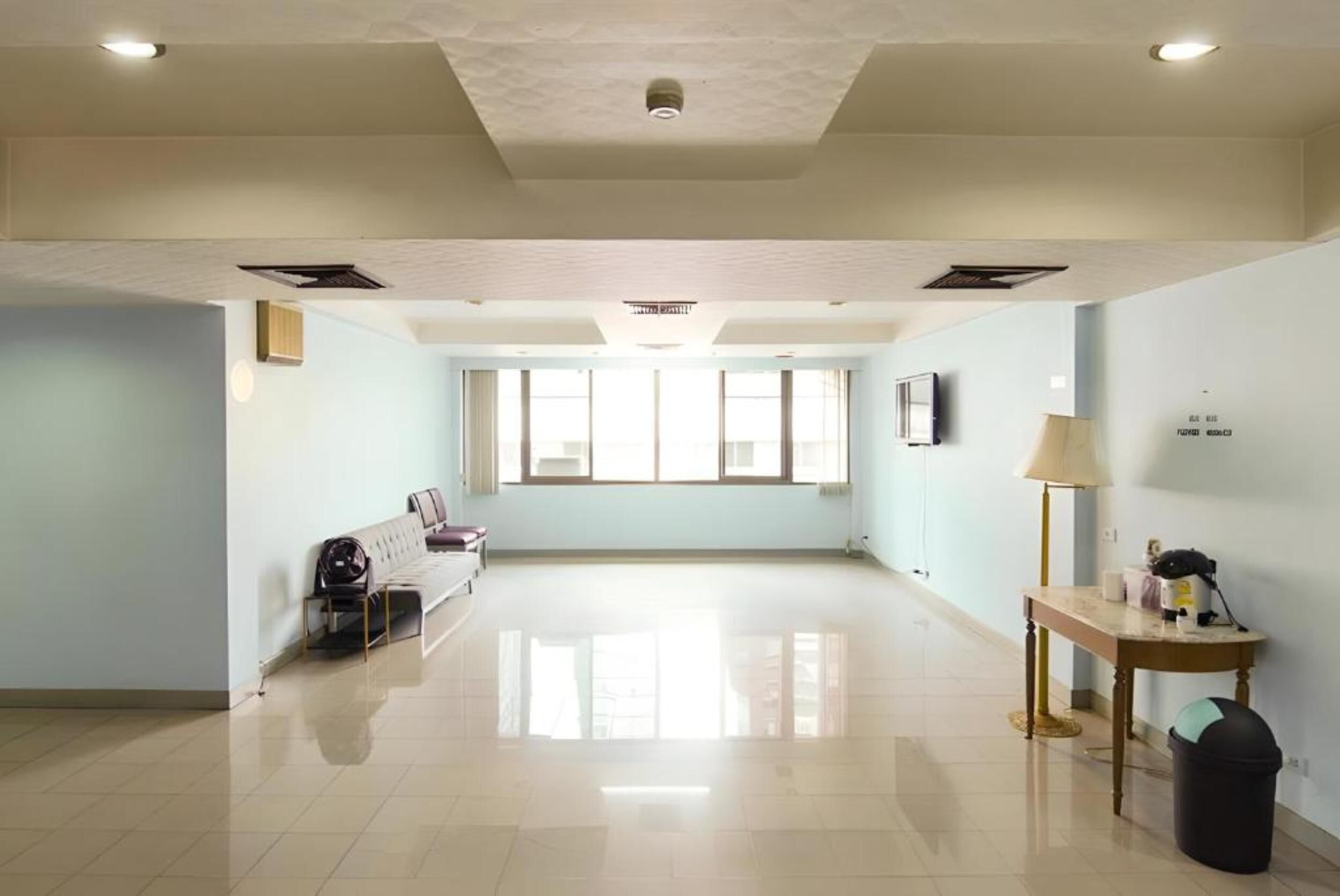 Una habitación amplia con sofá, una mesita y una lámpara.