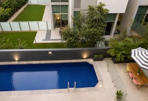 A modern outdoor swimming pool with a clear blue water surface, surrounded by a well-maintained lawn and a patio area with outdoor seating. - City Stay in Brisbane | Modern 2BR with Pool & Gym (Brisbane City)