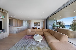 A modern living room with a sectional sofa, a coffee table, and a view of the ocean. - The Burleigh Coastal Luxe (Gold Coast)