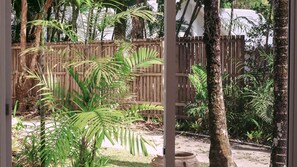 A wooden fence, palm trees, and a concrete planter in a garden setting. - Beach Shack Escape at Mission Beach – Walk to the Sand (Mission Beach)