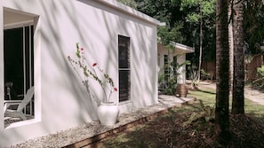 A white building with a window and a door, surrounded by trees and a gravel path. - Beach Shack Escape at Mission Beach – Walk to the Sand (Mission Beach)