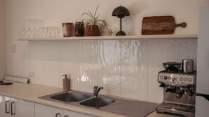 A kitchen with a double sink, a coffee machine, and a shelf with jars and a plant. - Beach Shack Escape at Mission Beach – Walk to the Sand (Mission Beach)