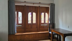 A room with a wooden bench, a table, and a view through a wooden door with glass panels. - Traditional 3-Bedroom Apartment Near Patan Square (Lalitpur)