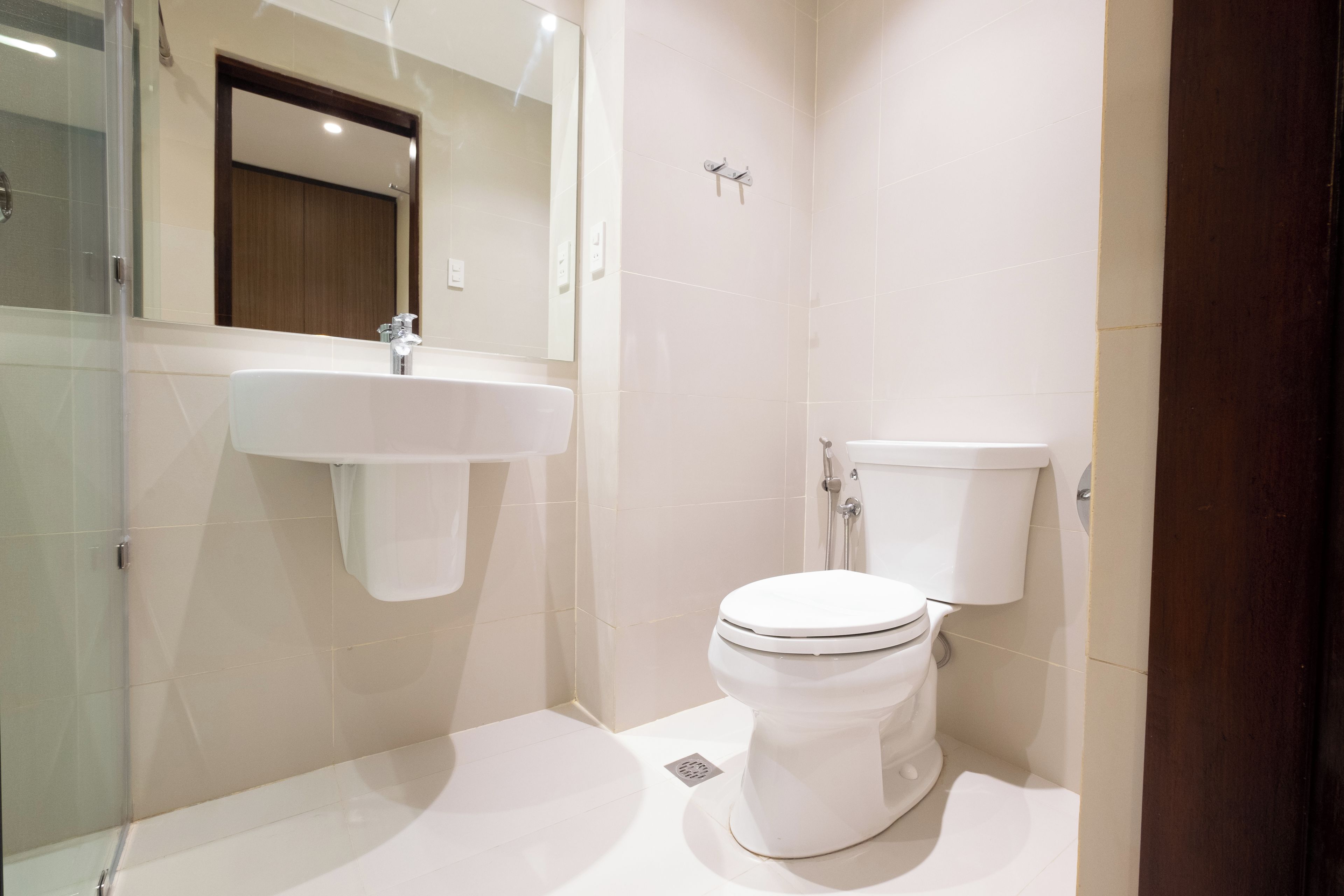 Un baño moderno con cabina de ducha de vidrio, un lavabo blanco y un inodoro.