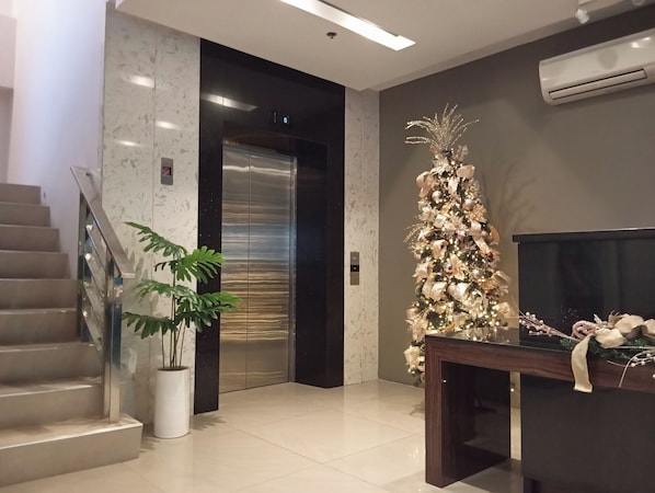 A modern lobby with a staircase, elevator, and a Christmas tree.
