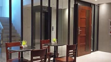 A modern dining area with a round table and four chairs, a potted plant, and a glass partition.