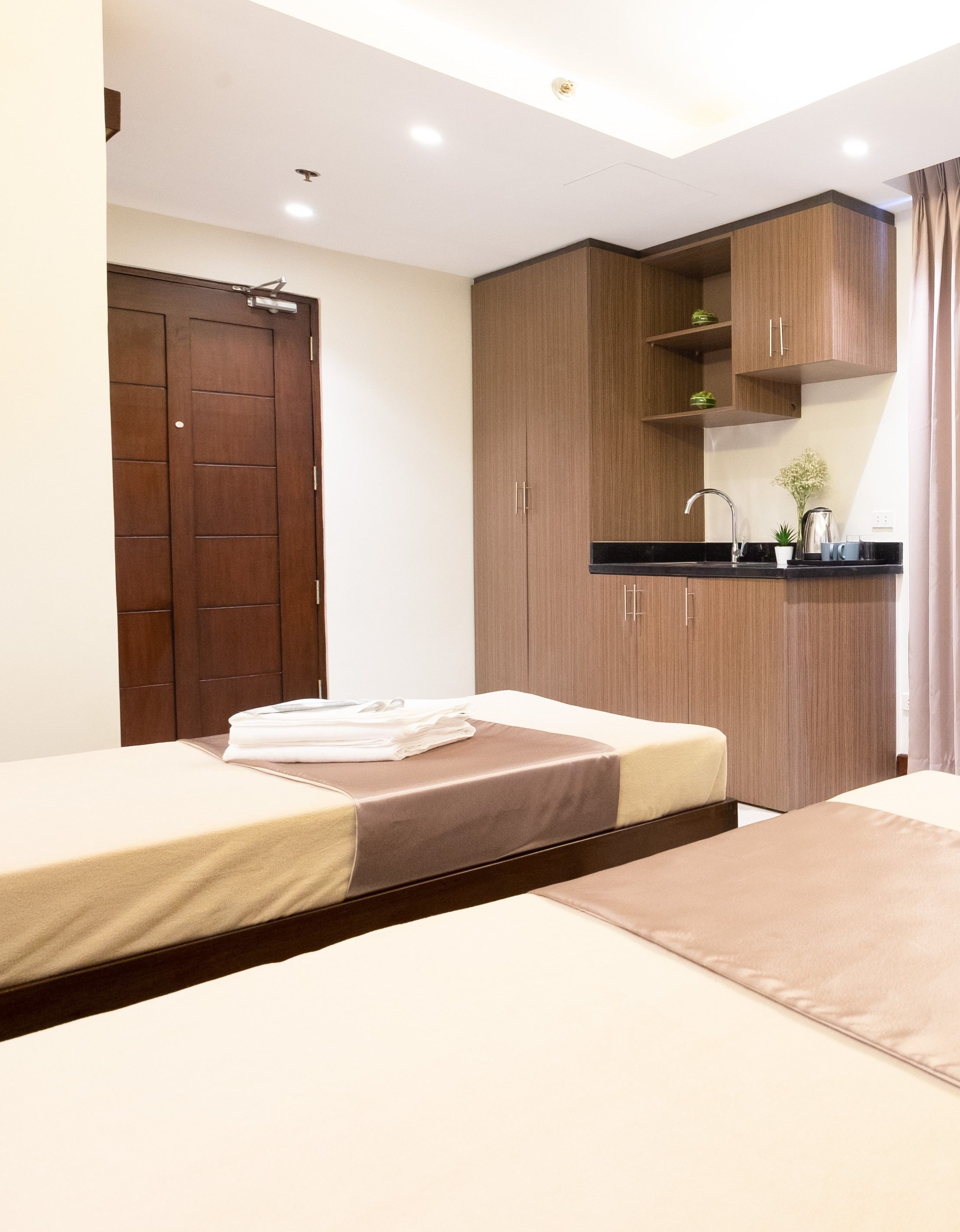 Una habitación de hotel con dos camas, kitchenette y baño.
