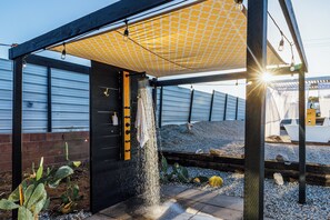 Un espacio al aire libre techado con una fuente de agua, una cerca de metal y una planta de cactus.