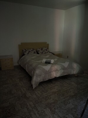 Ein Schlafzimmer mit einem Bett, zwei Nachttischen und einem Fliesenboden.