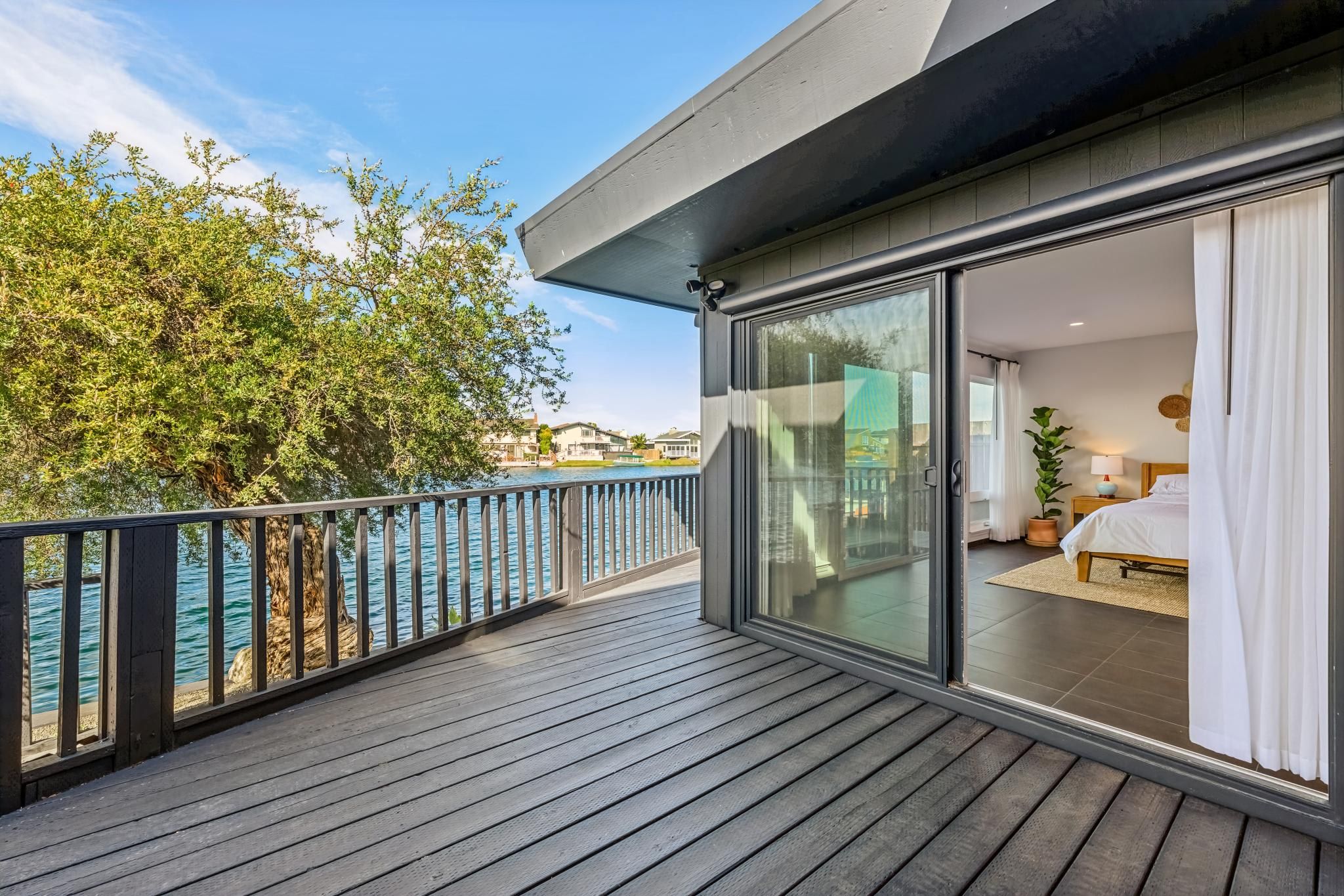 Un balcon donnant sur un plan d’eau et une zone résidentielle.