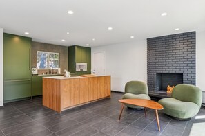 A modern kitchen with a wooden island, green chairs, and a fireplace. - Lagoonfront Home w/ Private Deck & Steam Shower (Foster City)