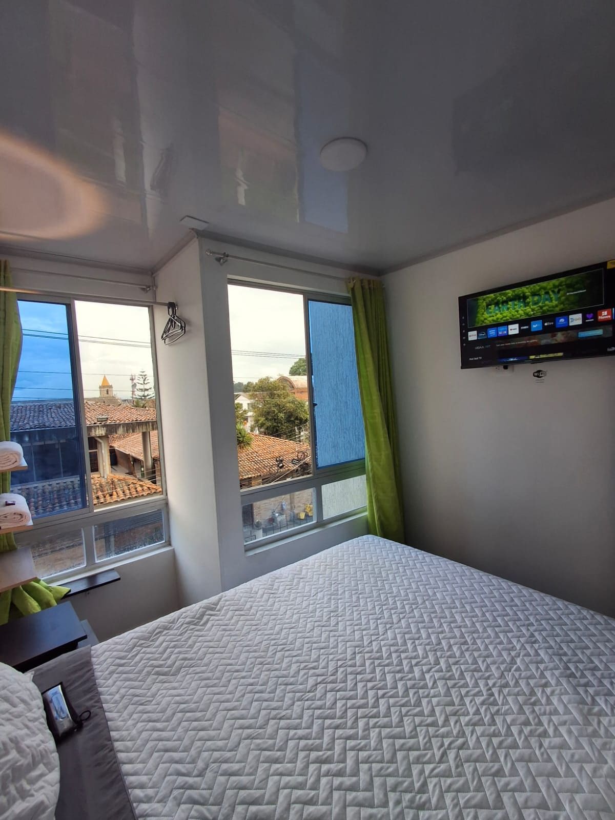 Ein Hotelzimmer mit Bett, Wandfernseher und einem Vorhangfenster.