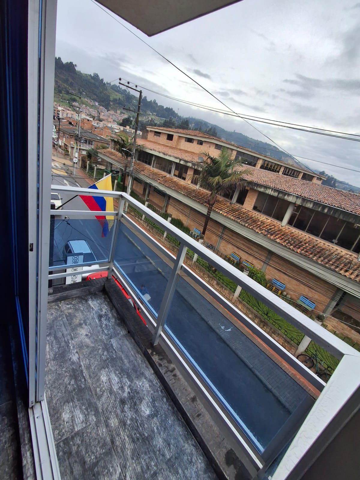 A balcony with a view of a residential area, including houses with tiled roofs and a street.