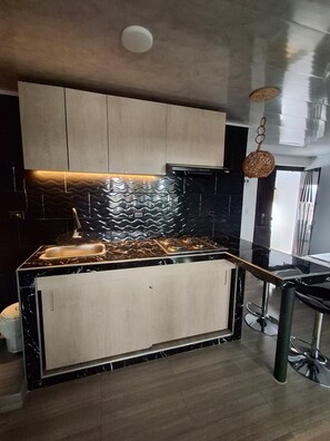 Een moderne keuken met een zwart aanrecht, een roestvrijstalen spoelbak en een spatwand met een golvend patroon.