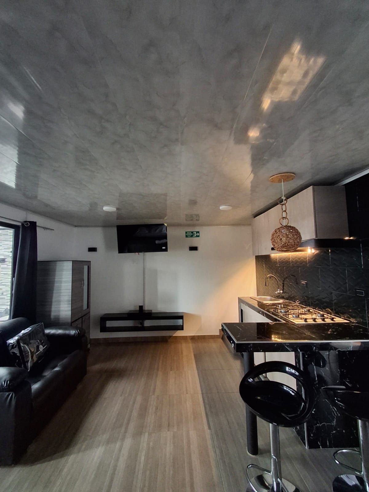 Een moderne keuken met een marmeren aanrecht, roestvrijstalen apparatuur en een hanglamp.