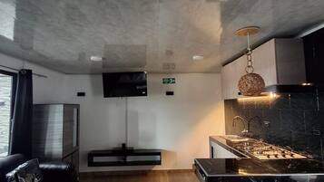 Een moderne keuken met een marmeren aanrecht, roestvrijstalen apparatuur en een hanglamp.