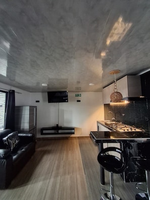 A modern kitchen with a marble countertop, stainless steel appliances, and a hanging light fixture. - Zig Zag hospedaje (Tocancipá)